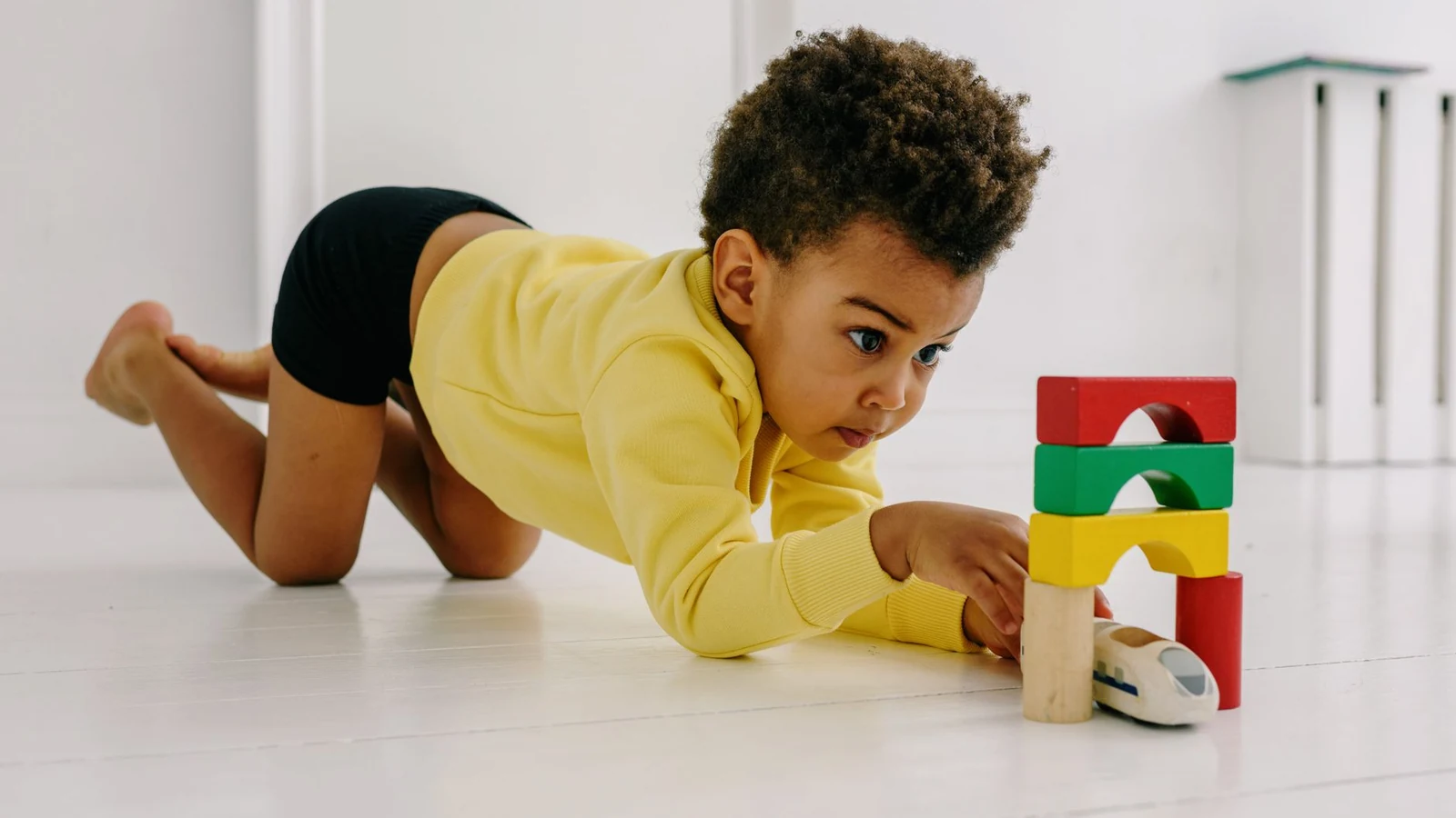 A toddler absorbed in building with wooden blocks on the floor