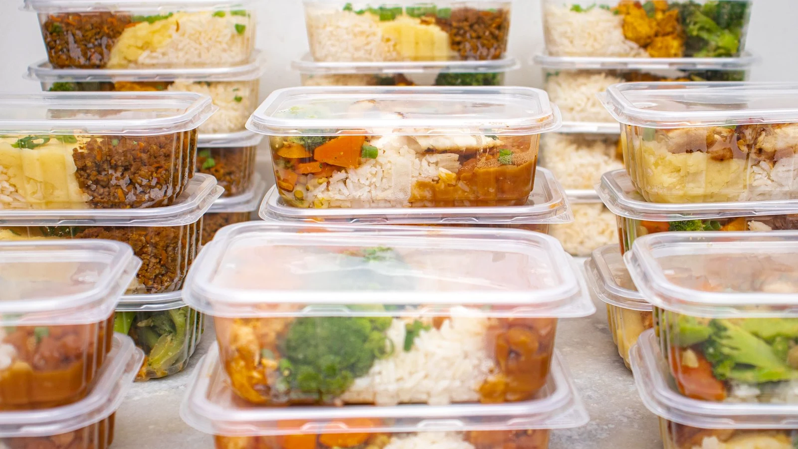 Individually portioned meals in clear containers, stacked and ready for the freezer