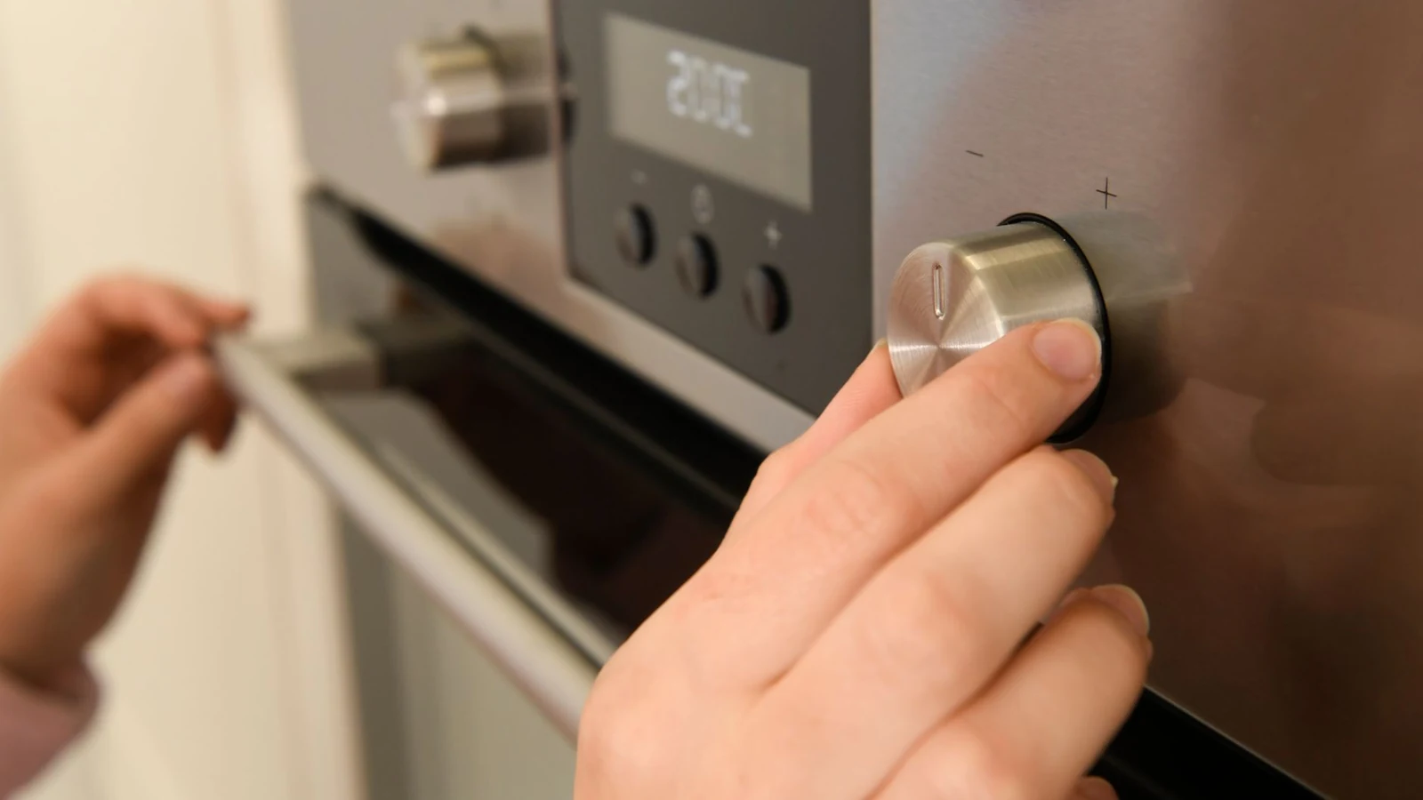 A hand turning a heat dial on a cooking appliance