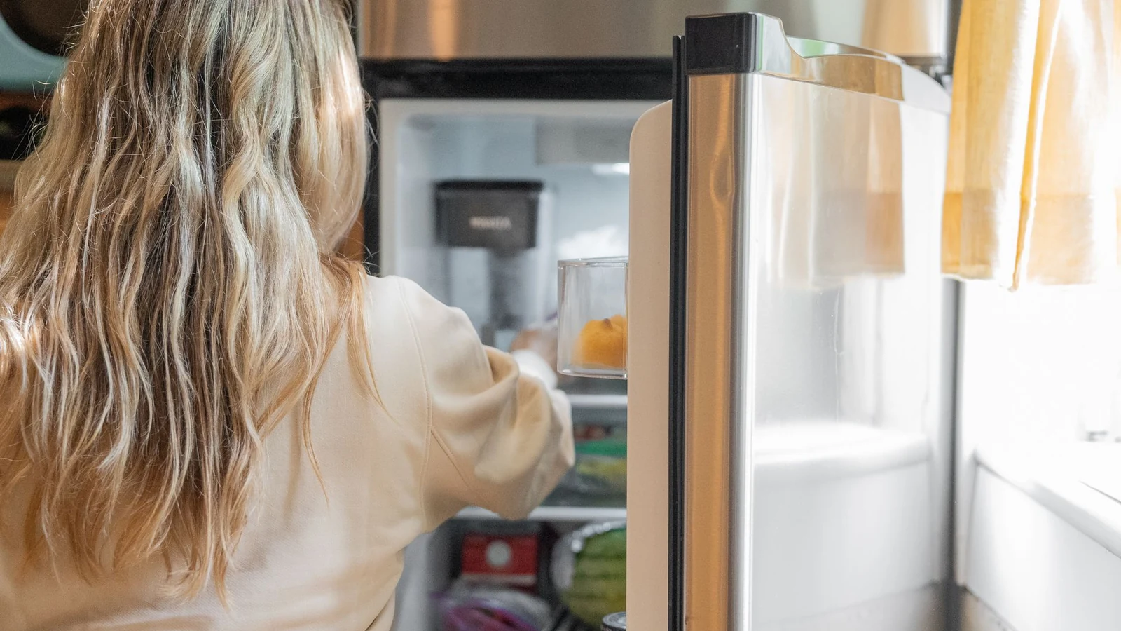 Someone reaching into a full open refrigerator