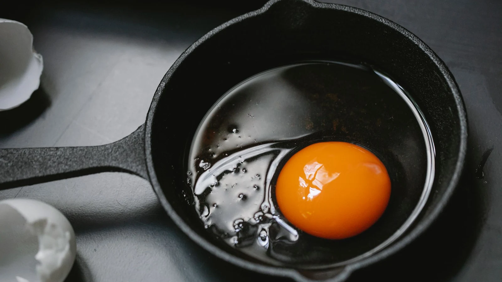 A top-down view of food cooking directly on a dark nonstick surface