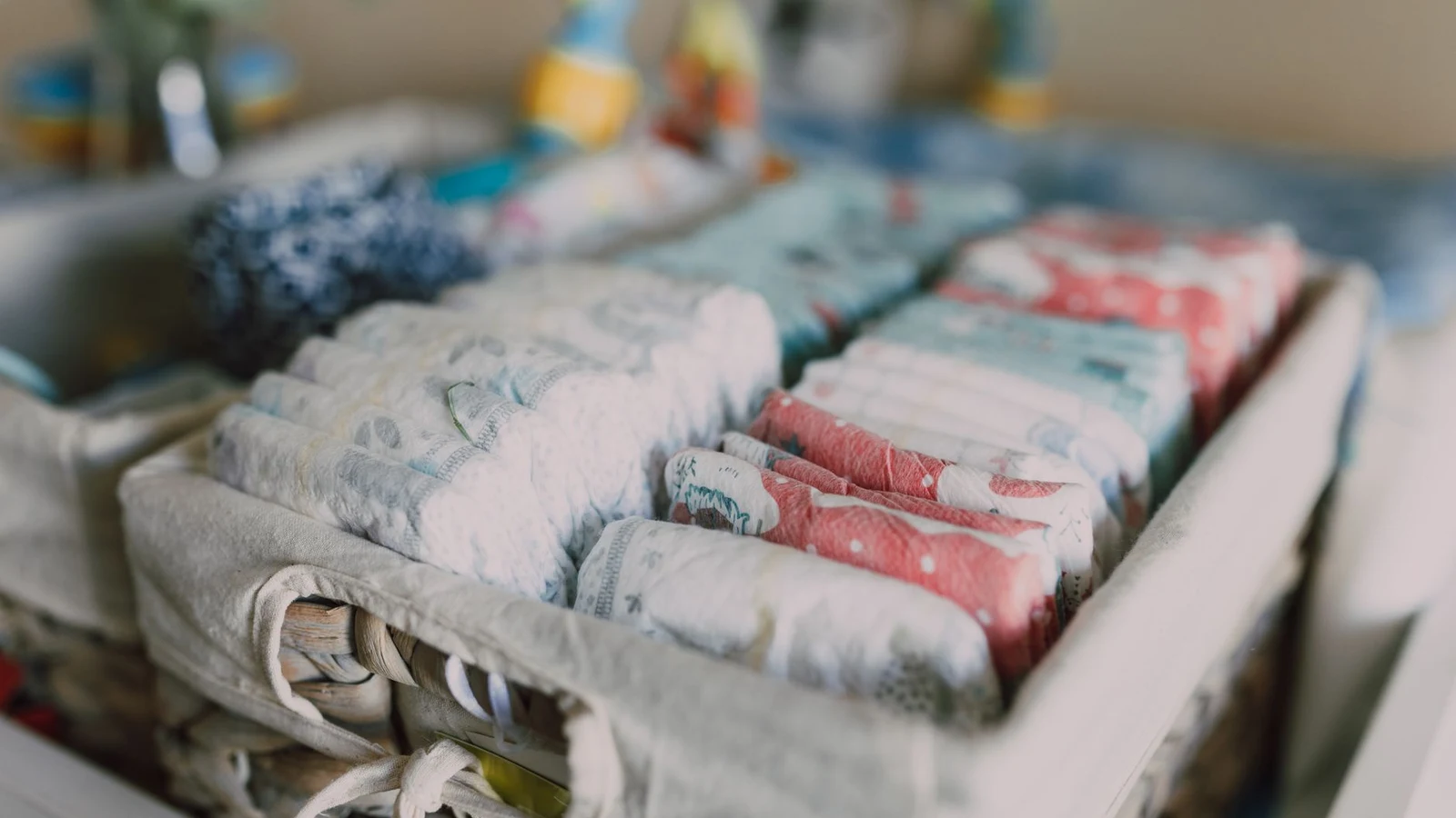 Newborn diapers and baby essentials neatly organized in a basket, ready before baby arrives